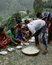a group of people sitting on the ground with food on plates