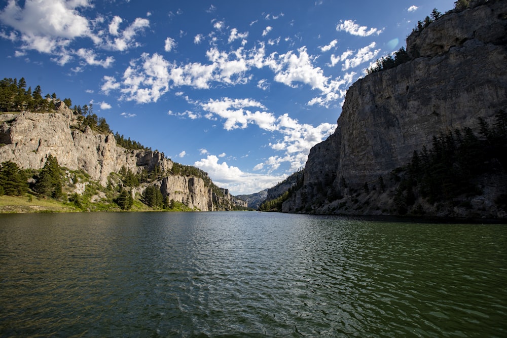 a body of water with cliffs and trees on the side