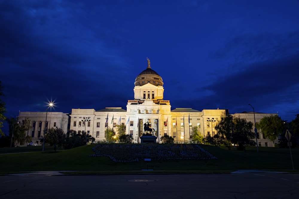 a large white building with a gold domed roof and a green lawn