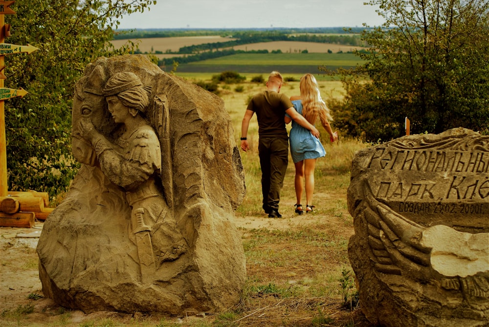 a man and woman standing next to a statue of a lion