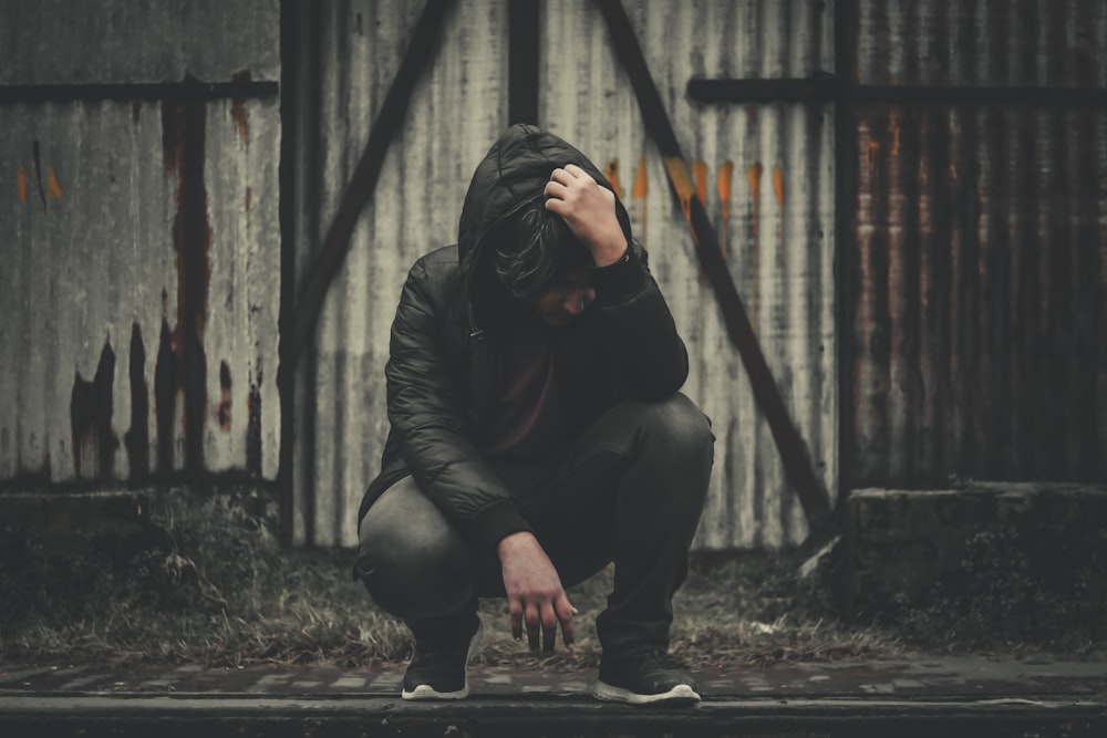 a woman squatting down with her head in her hands