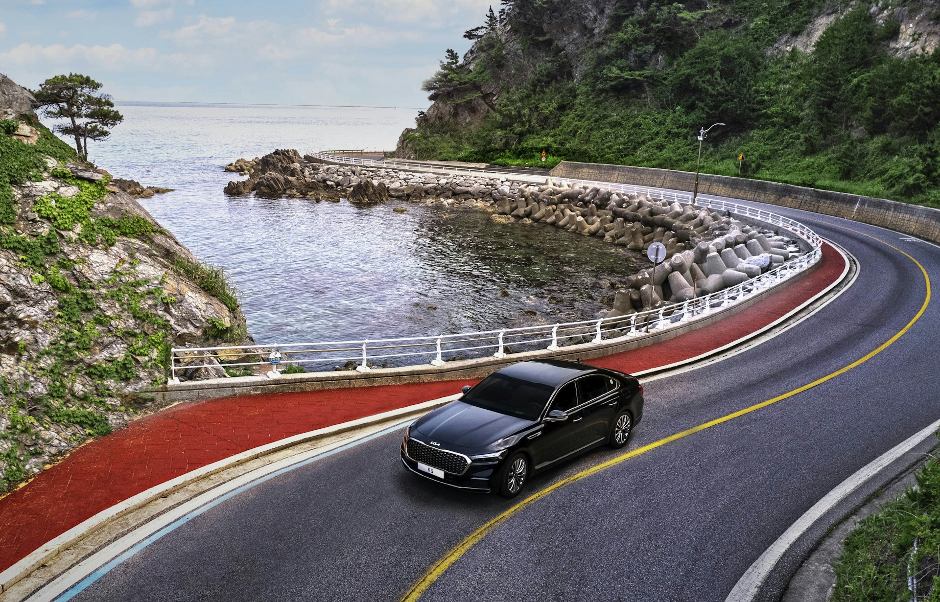 a black car driving on a road next to a body of water