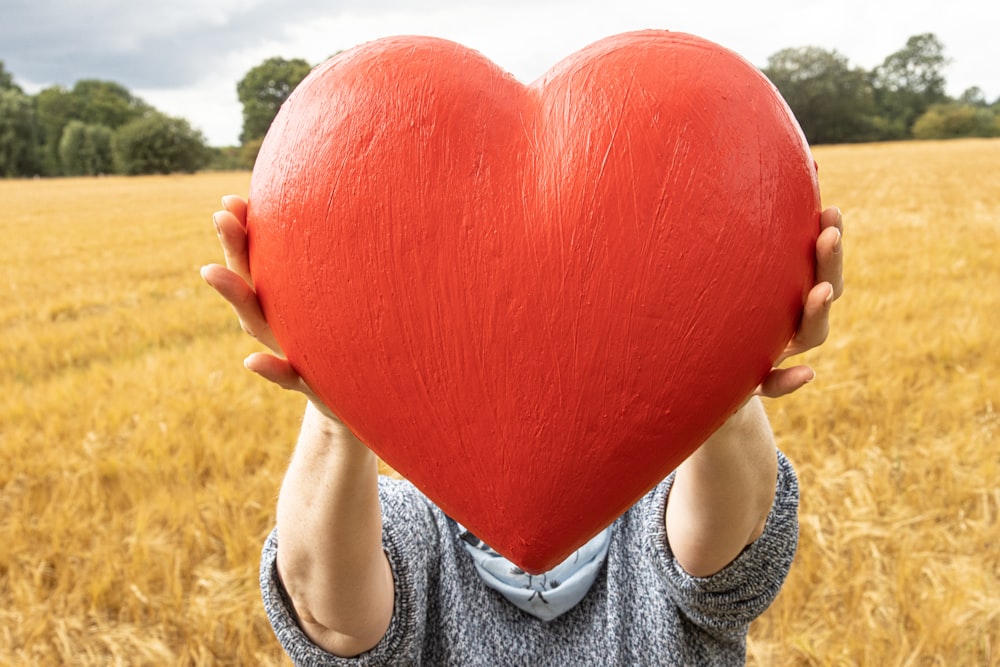 a person holding a large red fruit