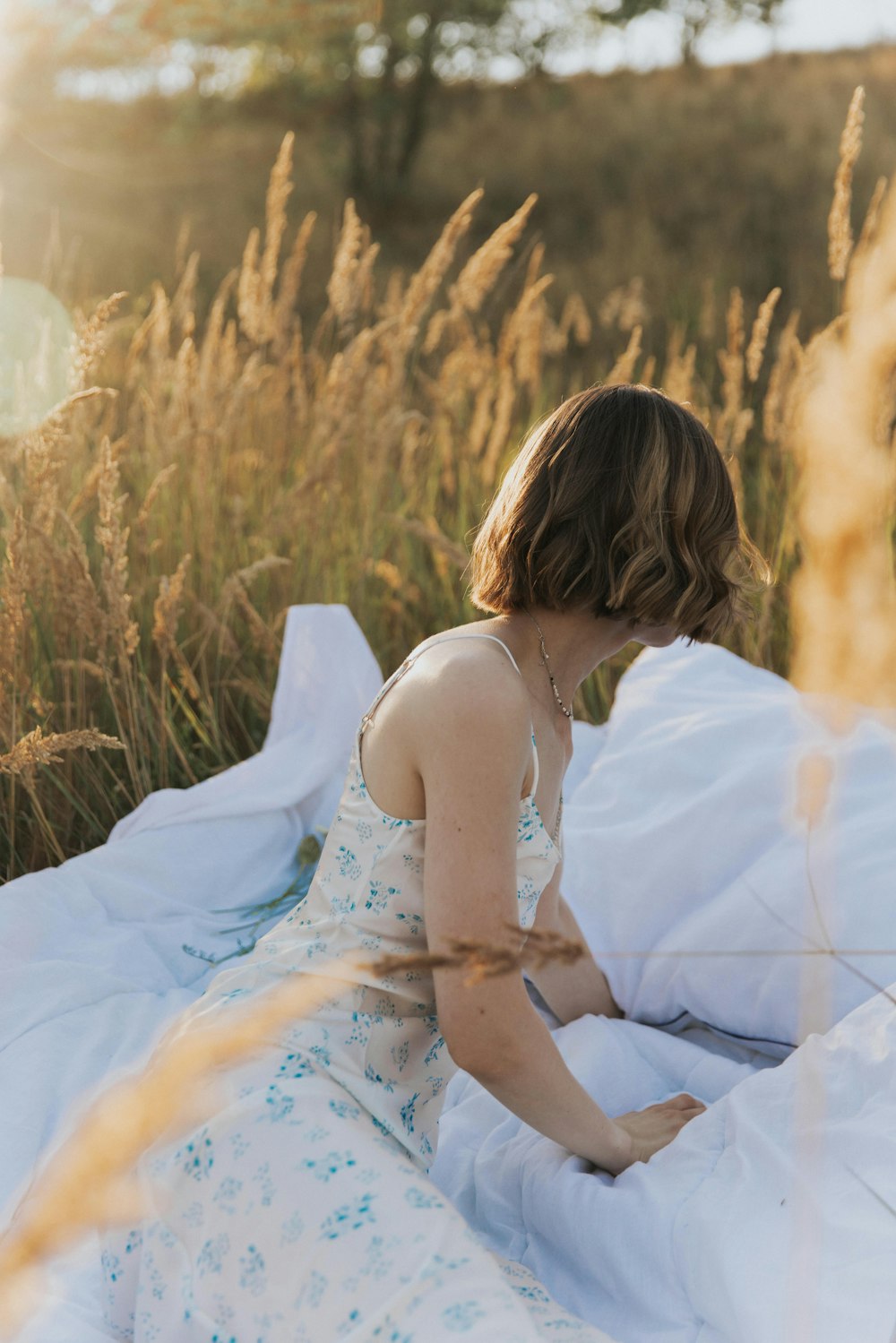 a woman in a white dress sitting in a field of wheat