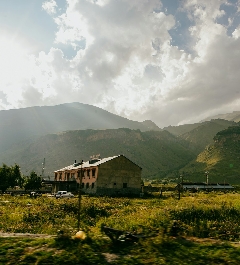 uma casa em um vale com montanhas ao fundo