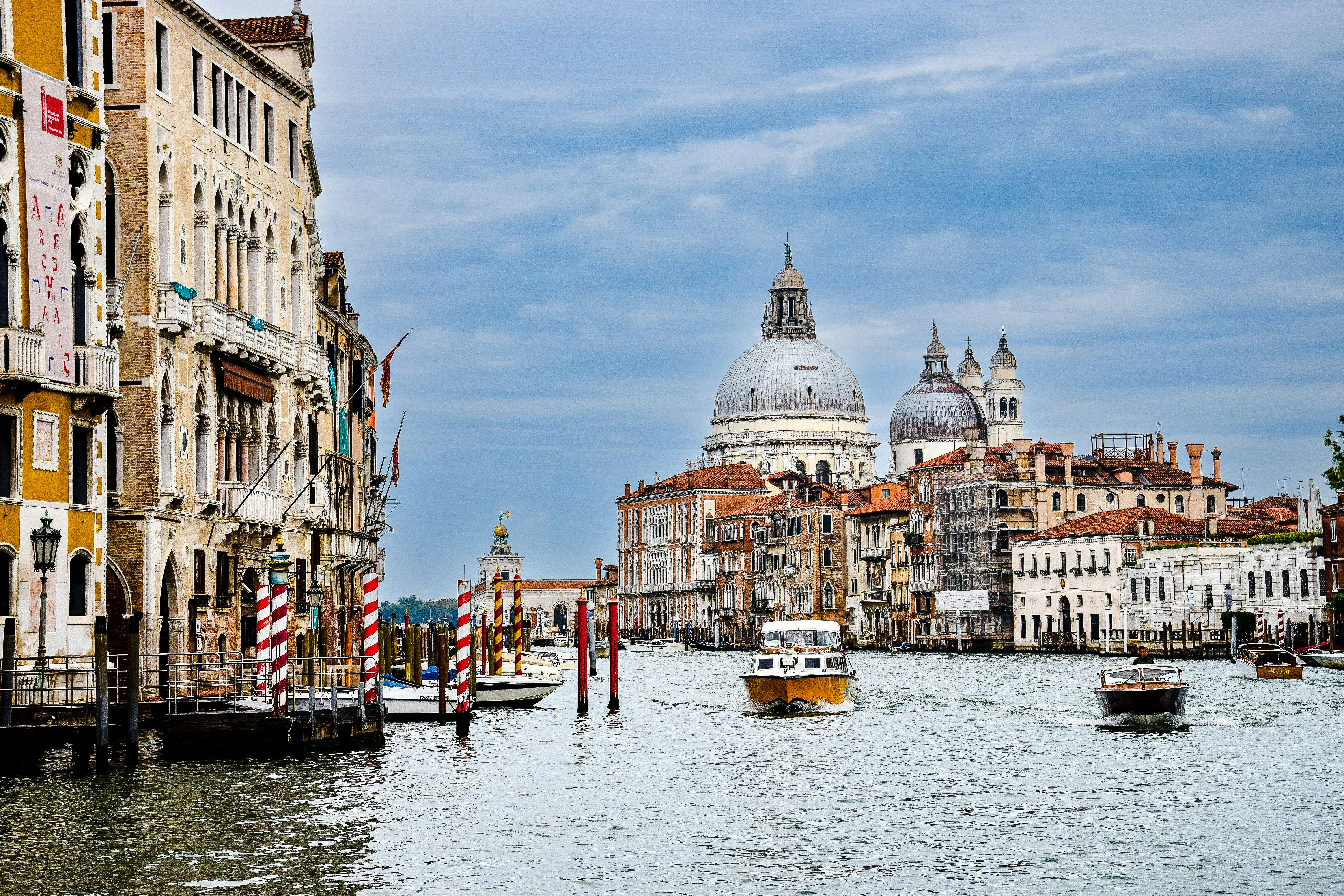 a body of water with boats in it and buildings around it, Cloudy Venice, Italy.