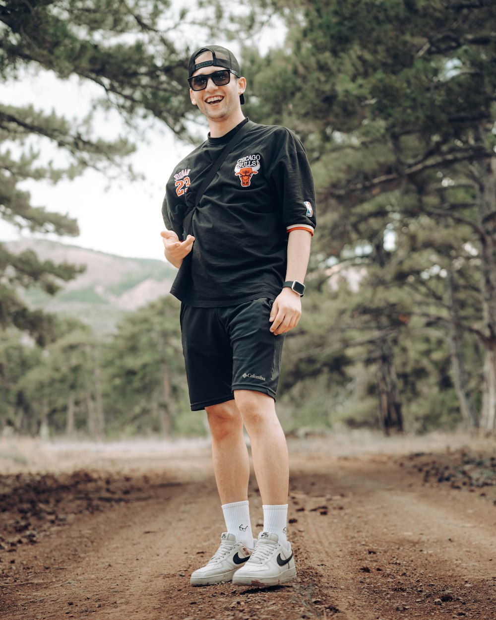 a man wearing sunglasses and standing on a dirt path