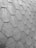 A close-up view of a roof with hexagonal asphalt shingles arranged in a repeating pattern. The texture is rough and appears consistent across the surface.