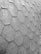 A close-up view of a roof with hexagonal asphalt shingles arranged in a repeating pattern. The texture is rough and appears consistent across the surface.