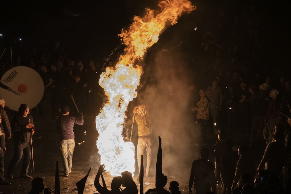 a group of people on a stage with a large fire