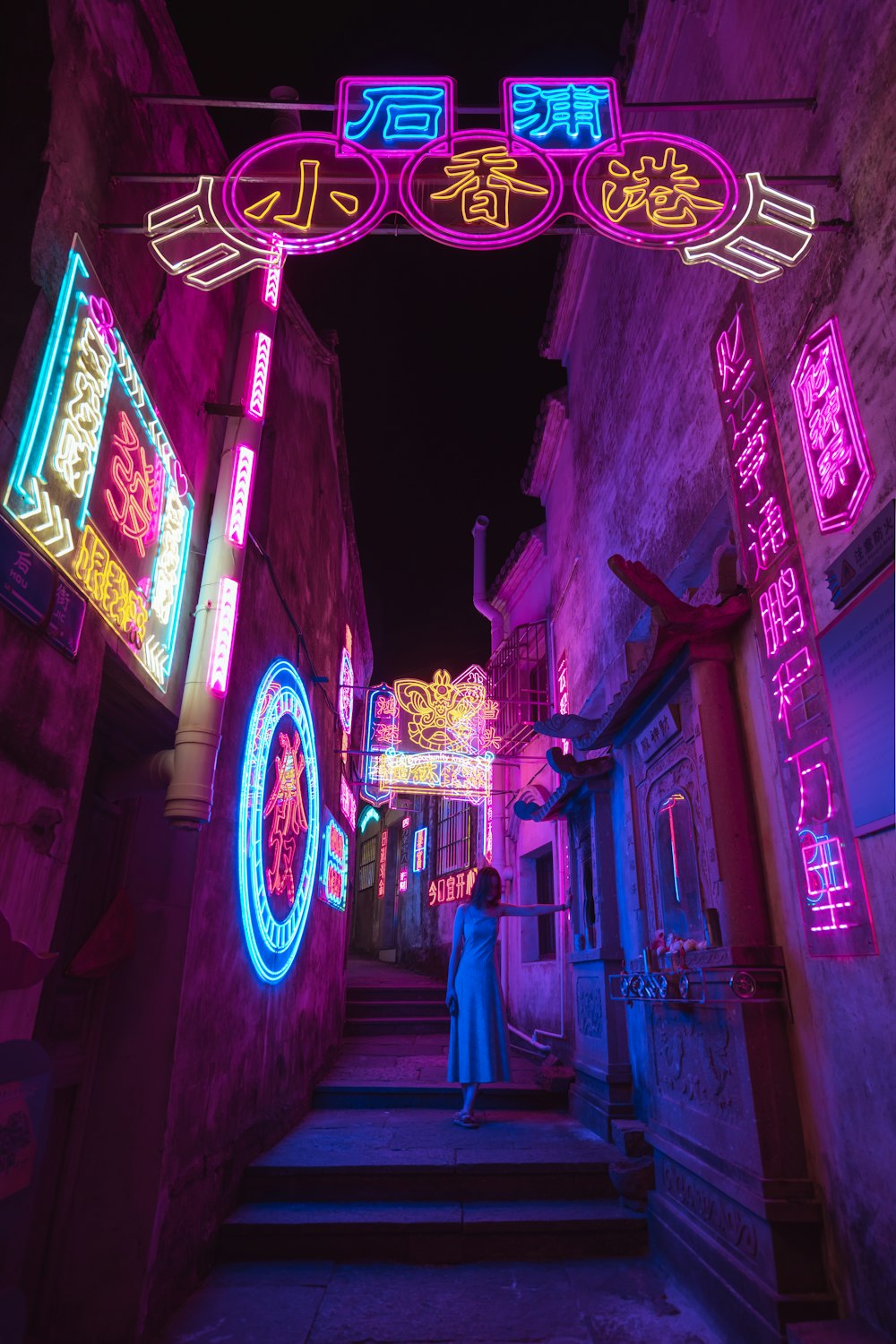 a person walking down a stairway in a lit up alley