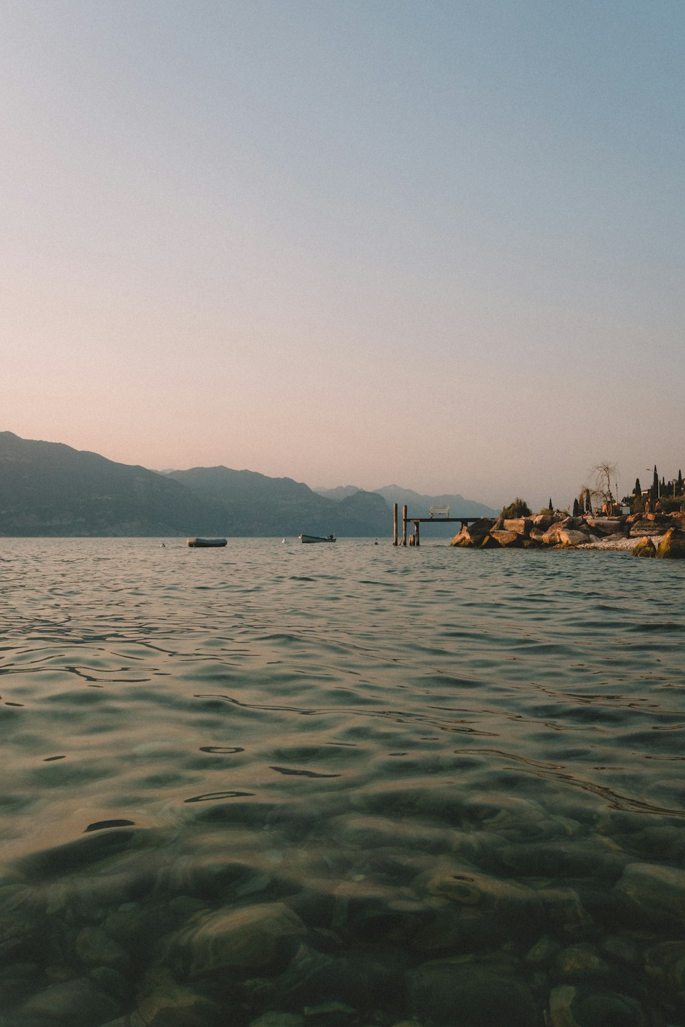 a body of water with boats in it and mountains in the background