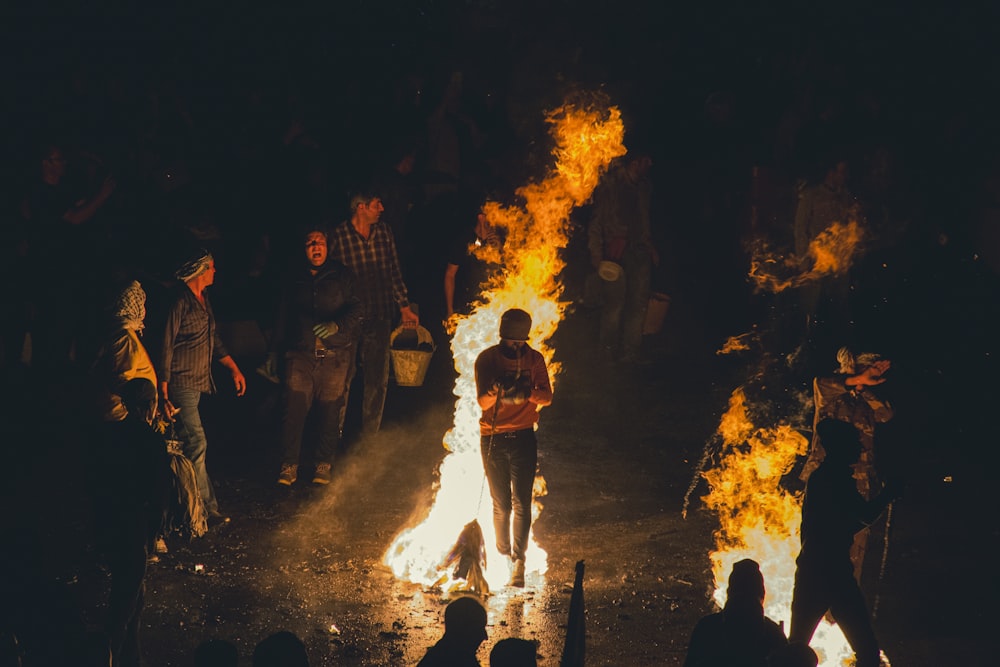 a group of people standing around a fire with Bonfires of Saint John in the background