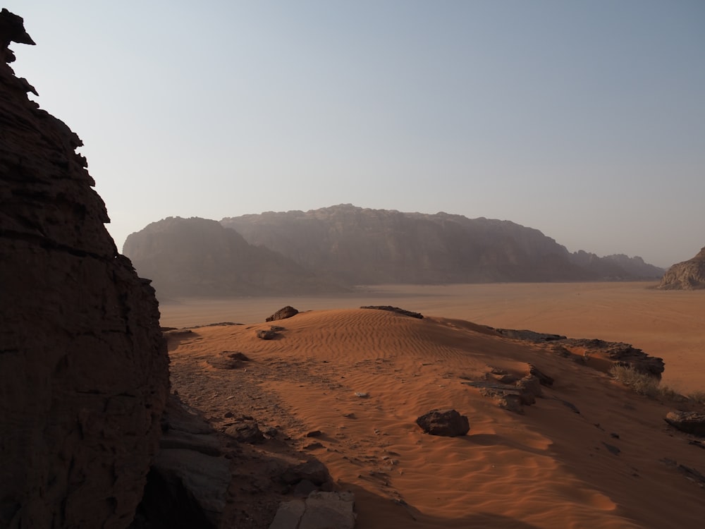 a sandy beach with hills in the background