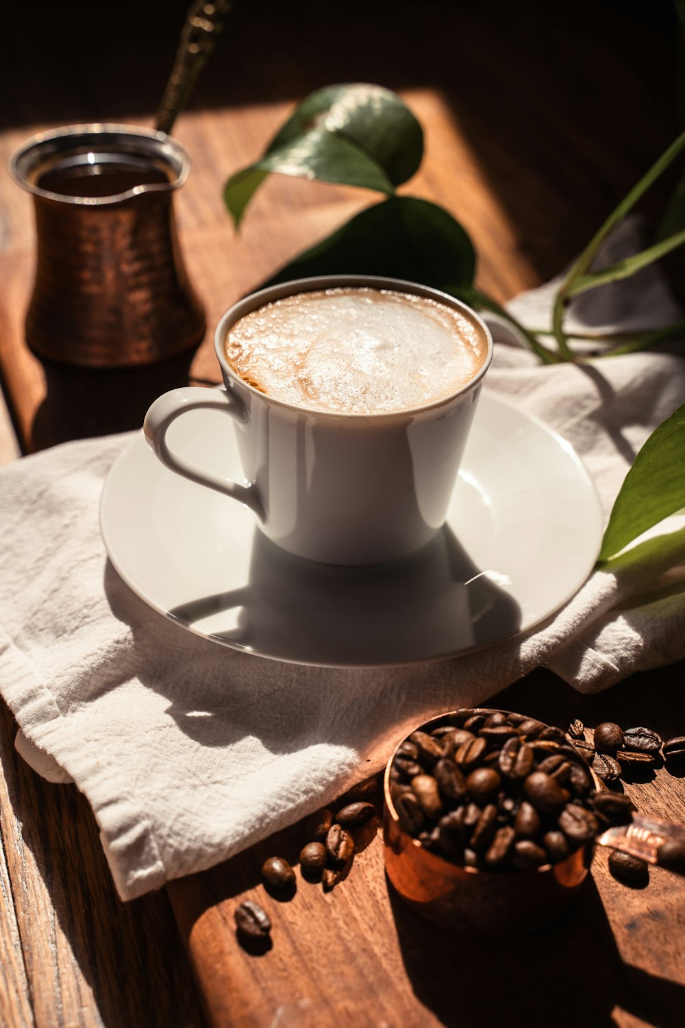 a cup of coffee and coffee beans on a table