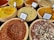 Various types of spices are displayed in wooden bowls, each labeled with their names. The spices include vibrant colors such as yellow, red, and mixtures of different spices. The labels identify them as Falafel Spice, Fish Spice, Harissa Spice, and Mixed Pepper, among others.