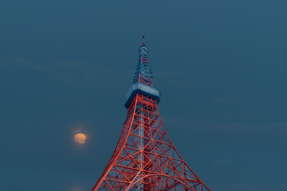 a tall metal tower with a bright moon in the sky