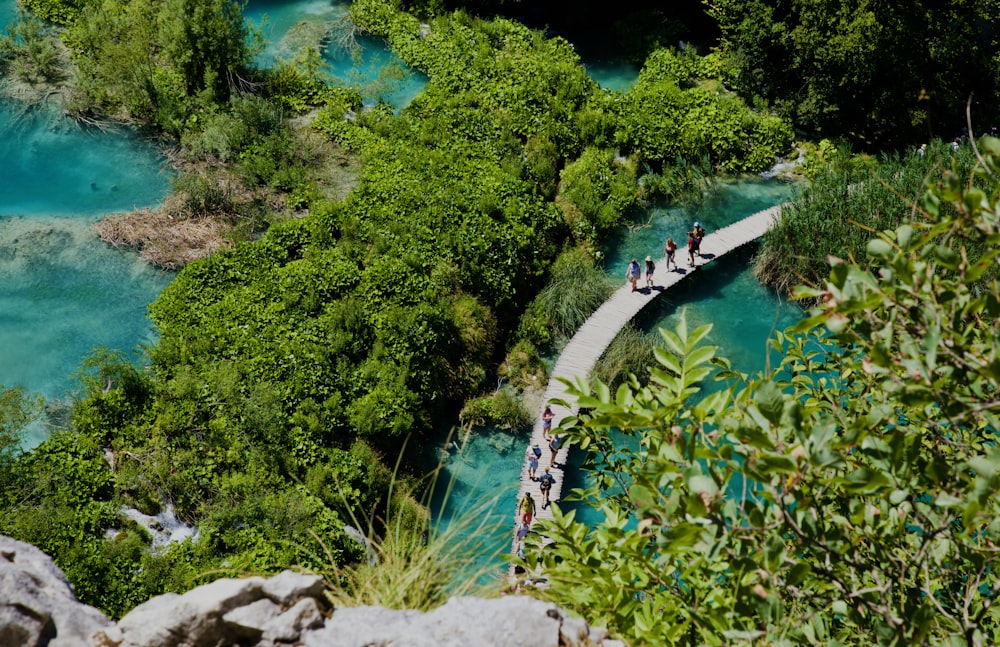 a group of people walking on a path by a body of water with Plitvice Lakes National Park in the background