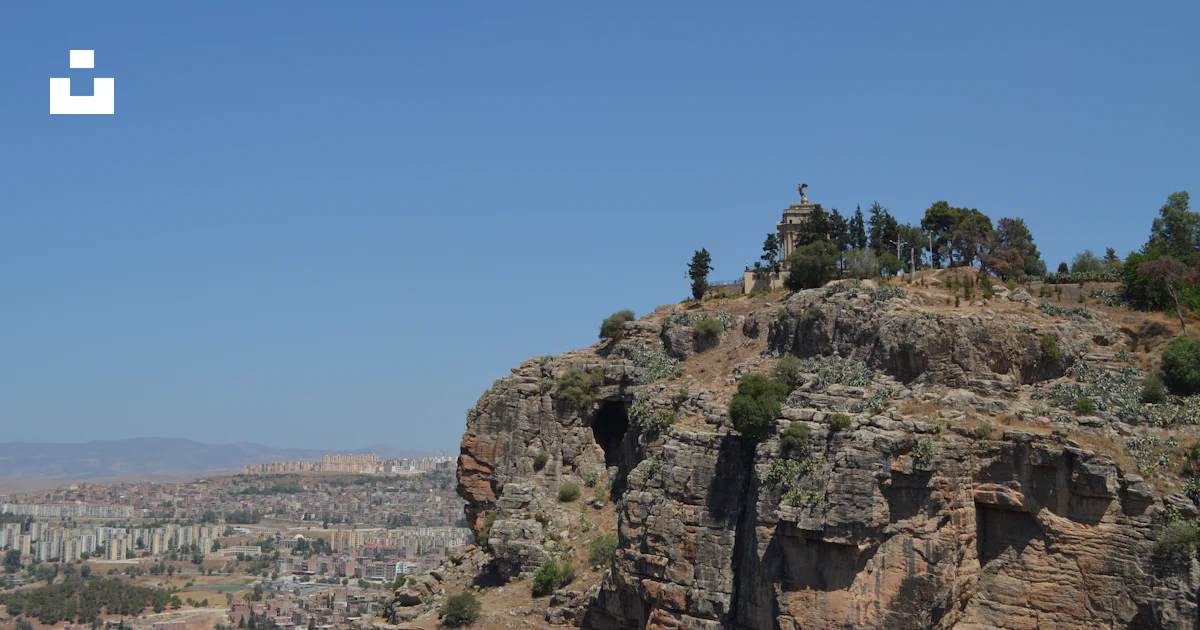 Foto Un gran acantilado de roca con una ciudad debajo – Imagen ...