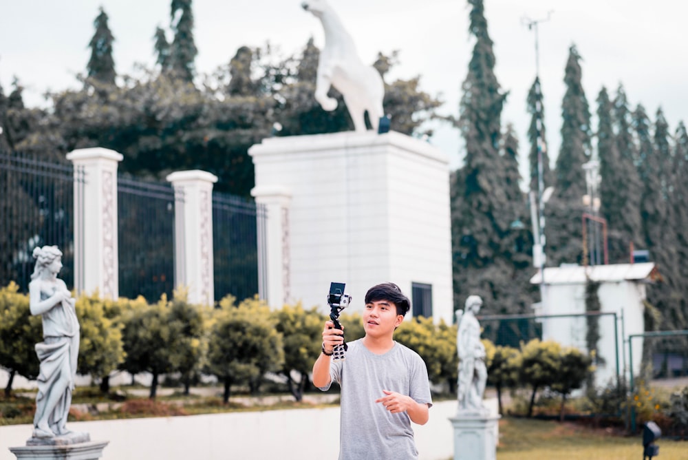 a man holding a microphone in front of a statue