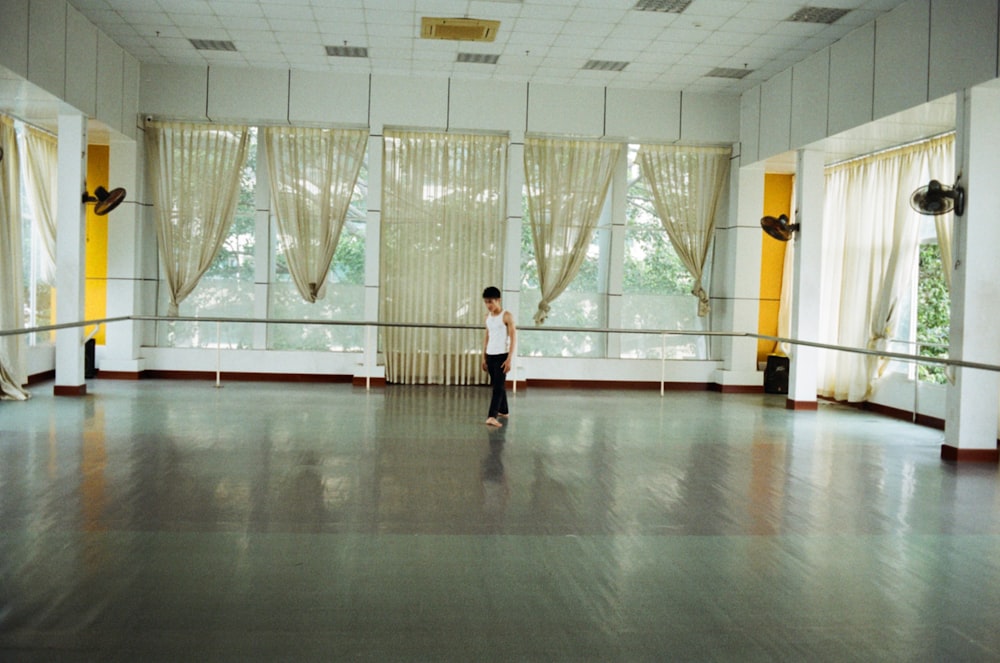 a person standing in a room with curtains and a large window