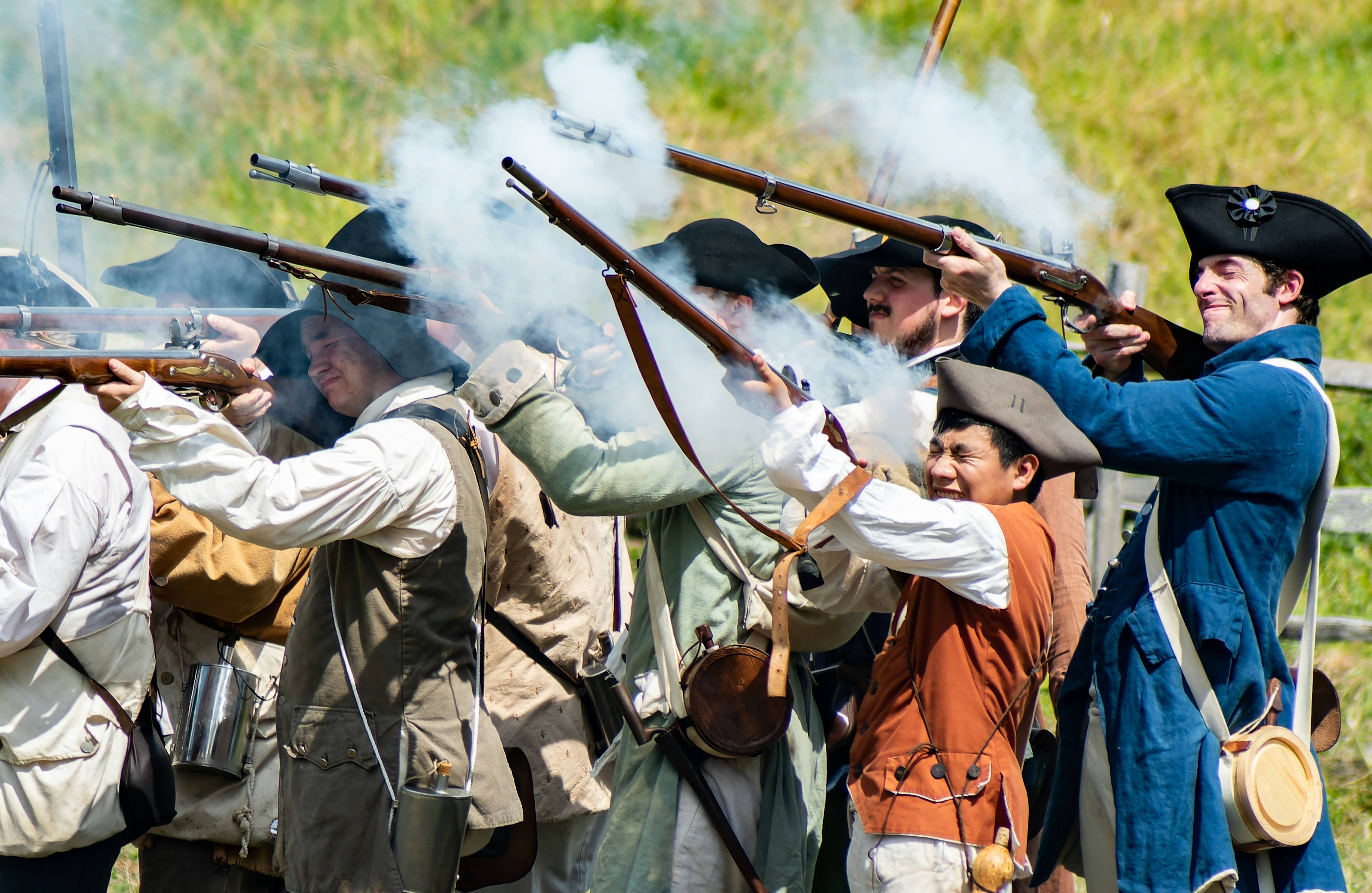 Revolutionary War reenactors firing muskets during a mock battle. This is an annual event at Old Sturbridge Village, Sturbridge, MA, USA