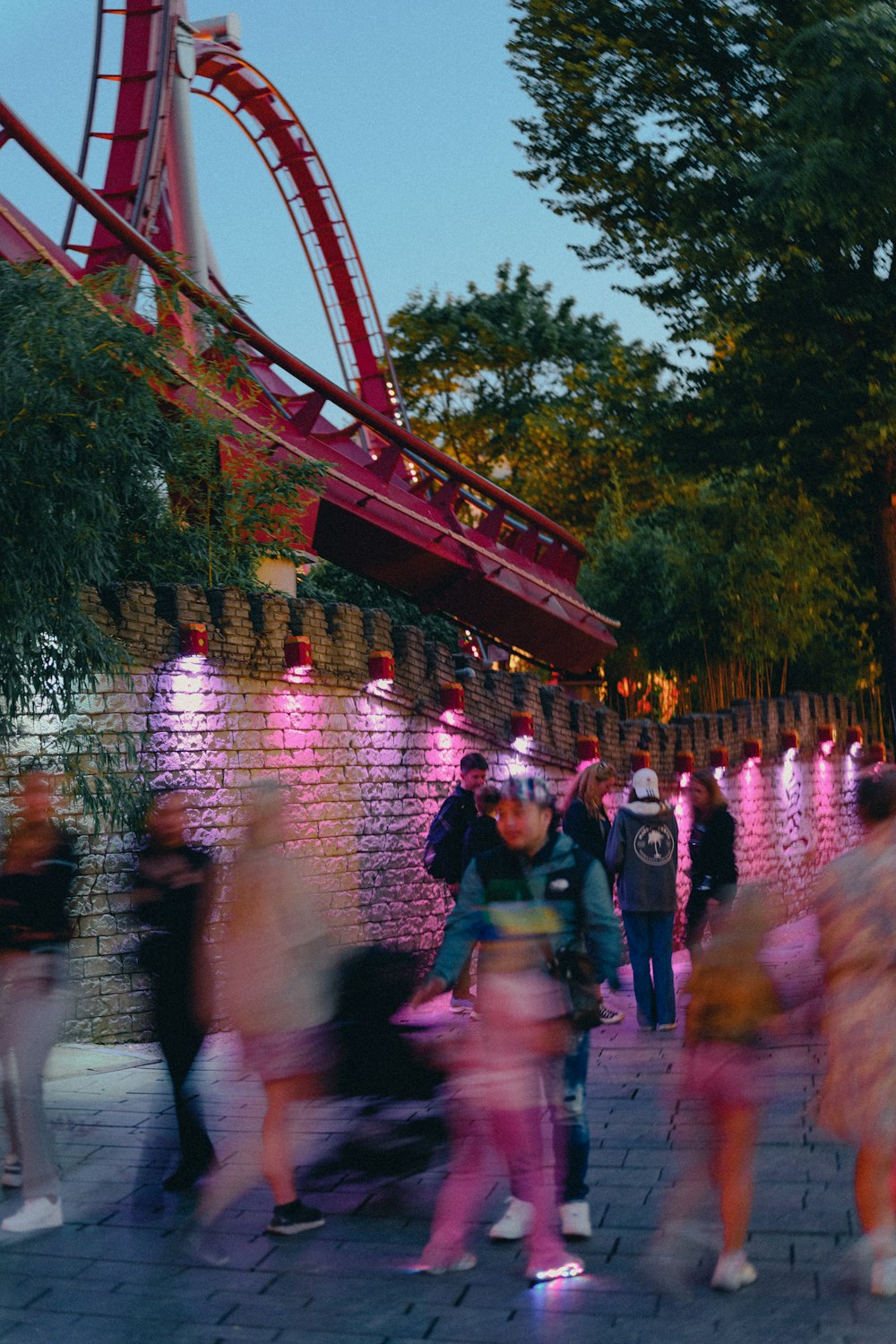 a group of people walking on a sidewalk next to a red structure