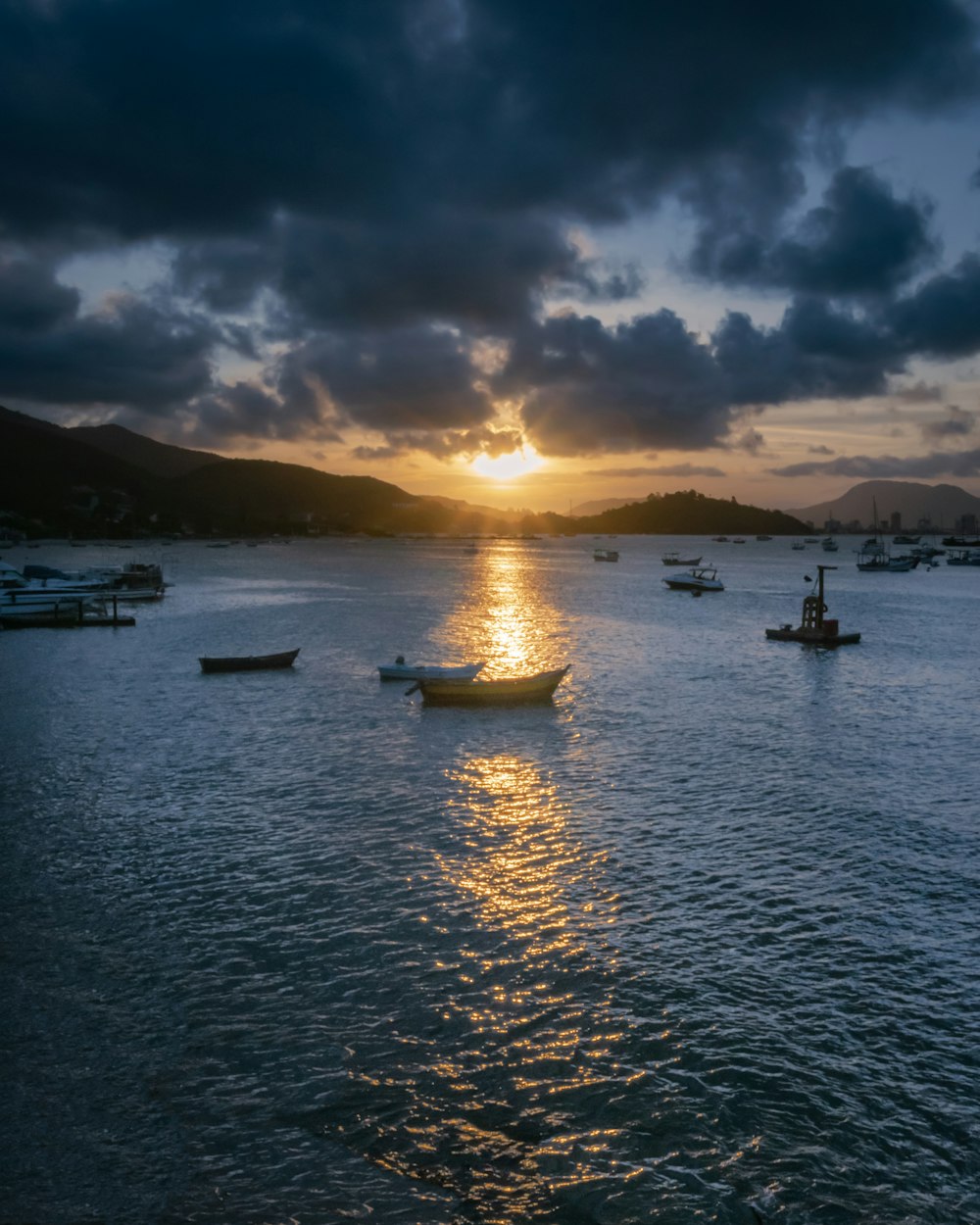 Un groupe de bateaux dans un plan d’eau avec un coucher de soleil