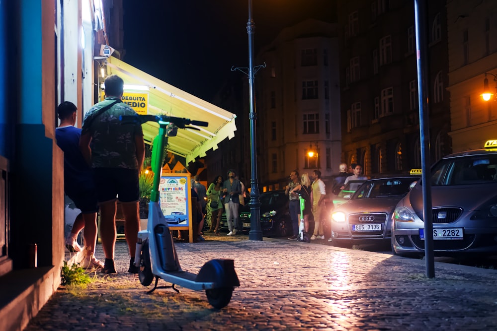 a group of people standing on a sidewalk next to a food stand