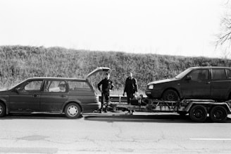 a couple of men standing next to a couple of cars with surfboards