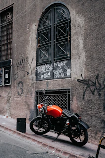 A high-performance bike with safety orange accents speeding past graffiti walls in slow motion