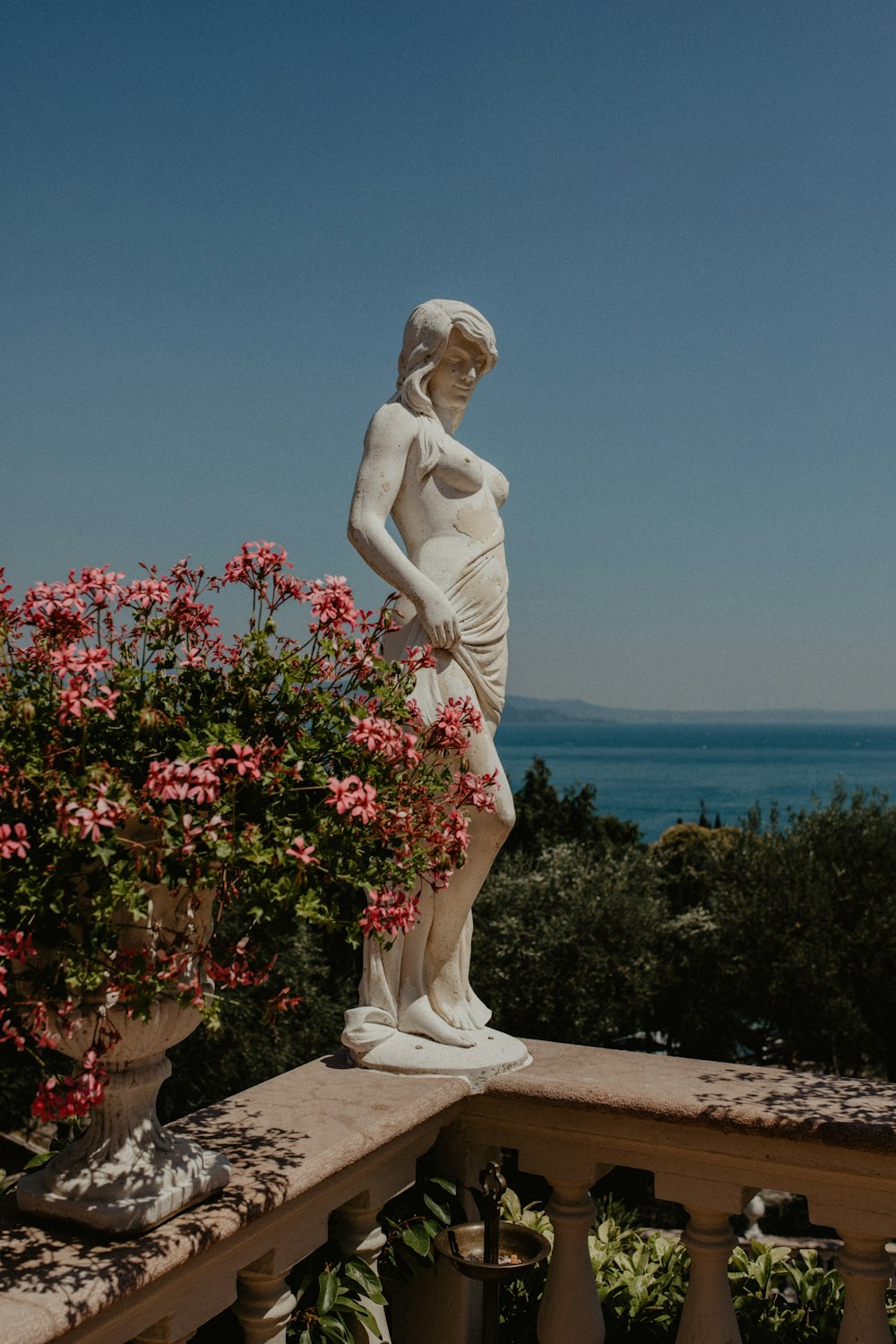 a statue of a person on a ledge overlooking a body of water