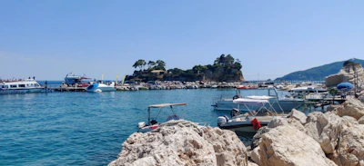 A scenic view of Labuan Bajo harbor with colorful boats and crystal-clear waters under a bright blue sky.