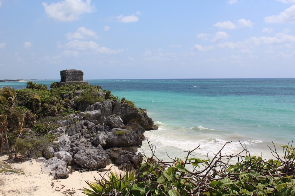 a rocky beach with a castle on it with Tulum in the background