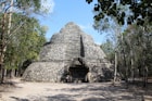 a stone building with a door with Coba in the background
