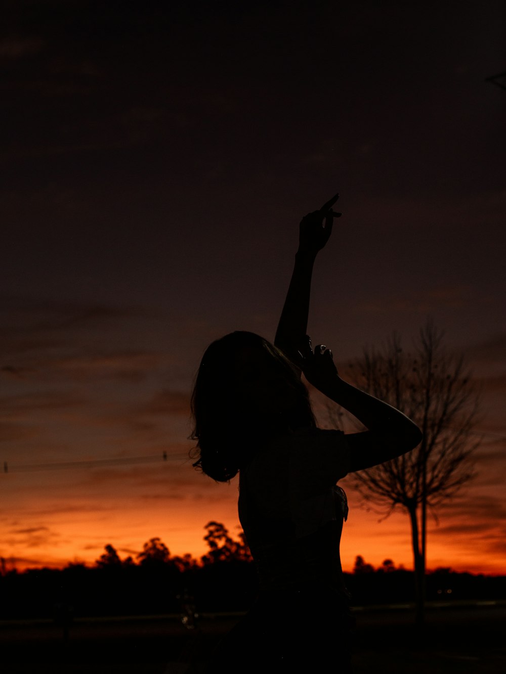 a statue of a person holding the hand up in front of a sunset