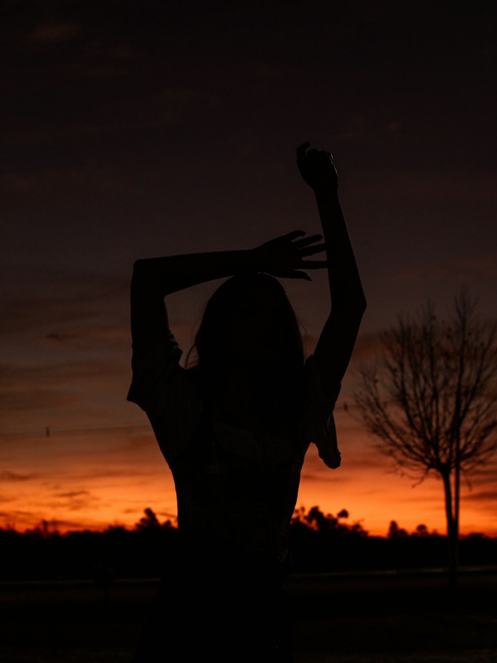 a silhouette of a man holding his hands up in front of a sunset