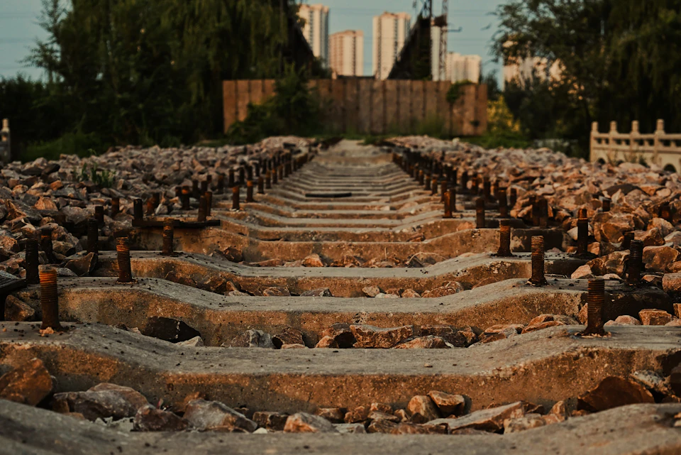 Rusted metal rails and wooden ties line a train track stretching into the distance