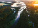 Lush green rainforest landscape with a winding river under a soft sunset.
