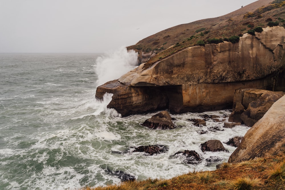 a rocky cliff next to a body of water