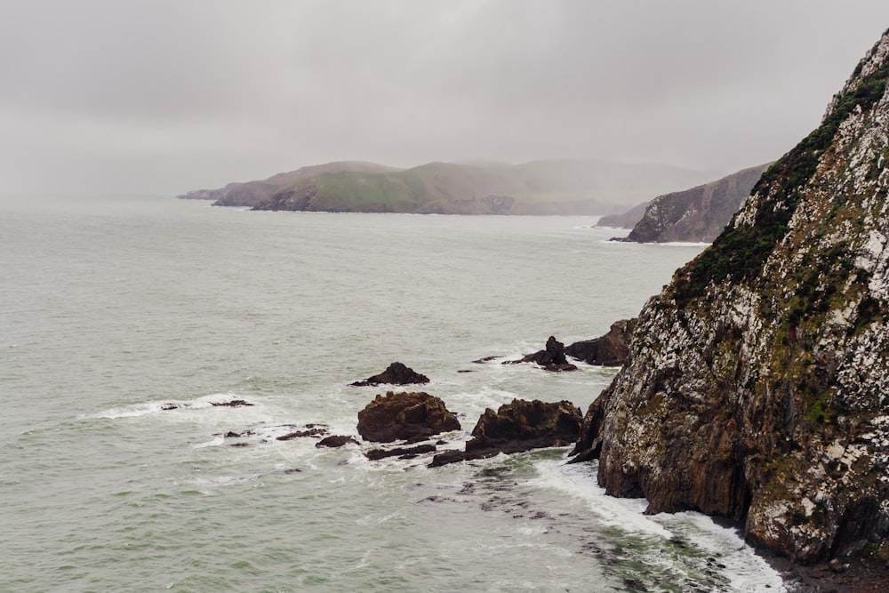 a rocky beach with a body of water in the background