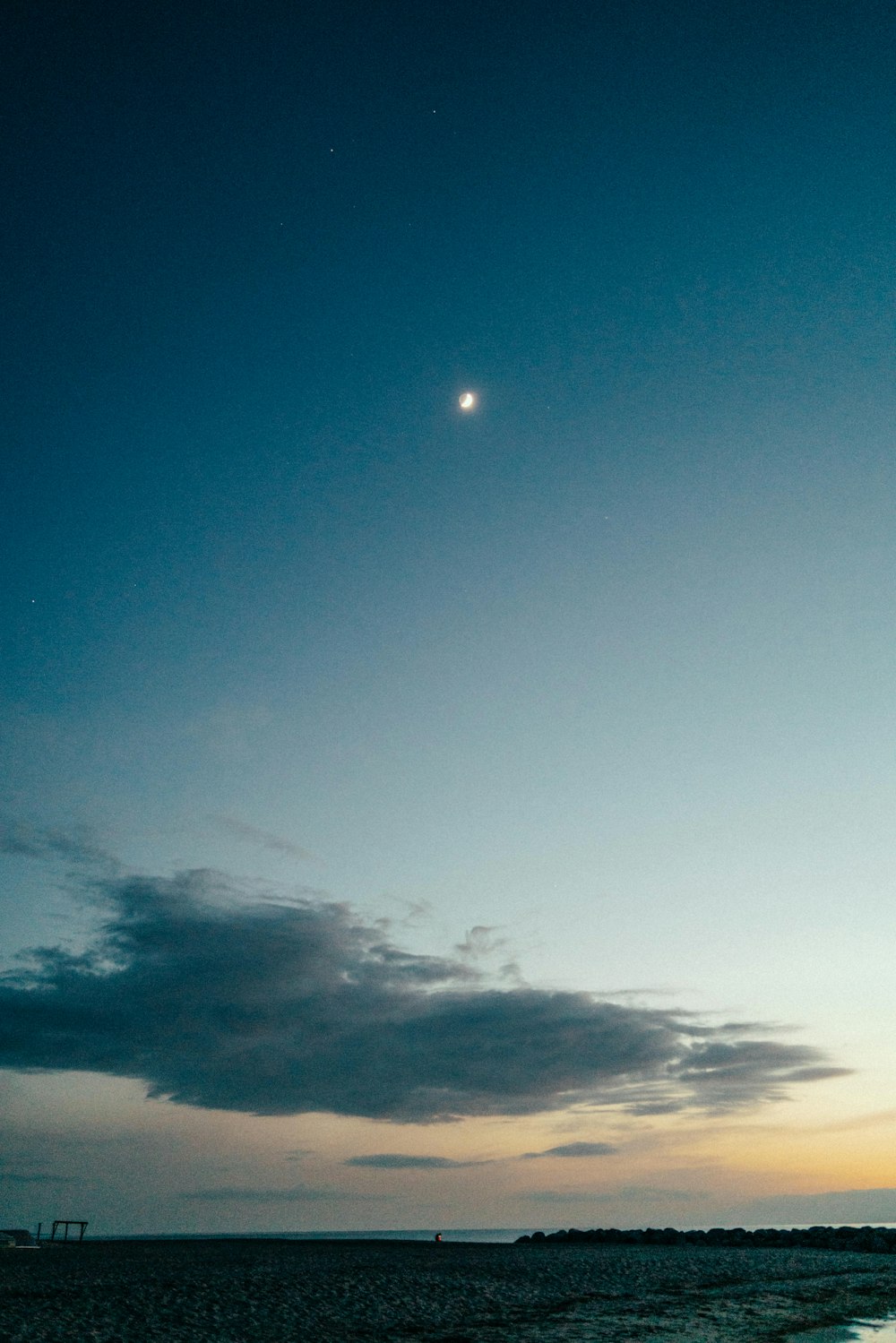 a body of water with a moon in the sky above it