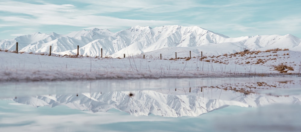 a snowy landscape with a body of water and mountains in the background