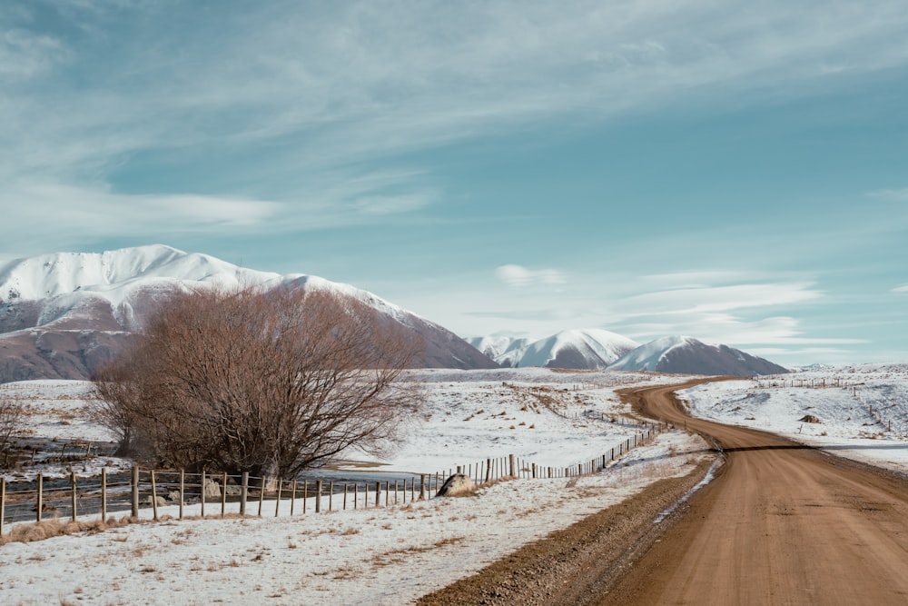 a road with snow on the side and mountains in the background