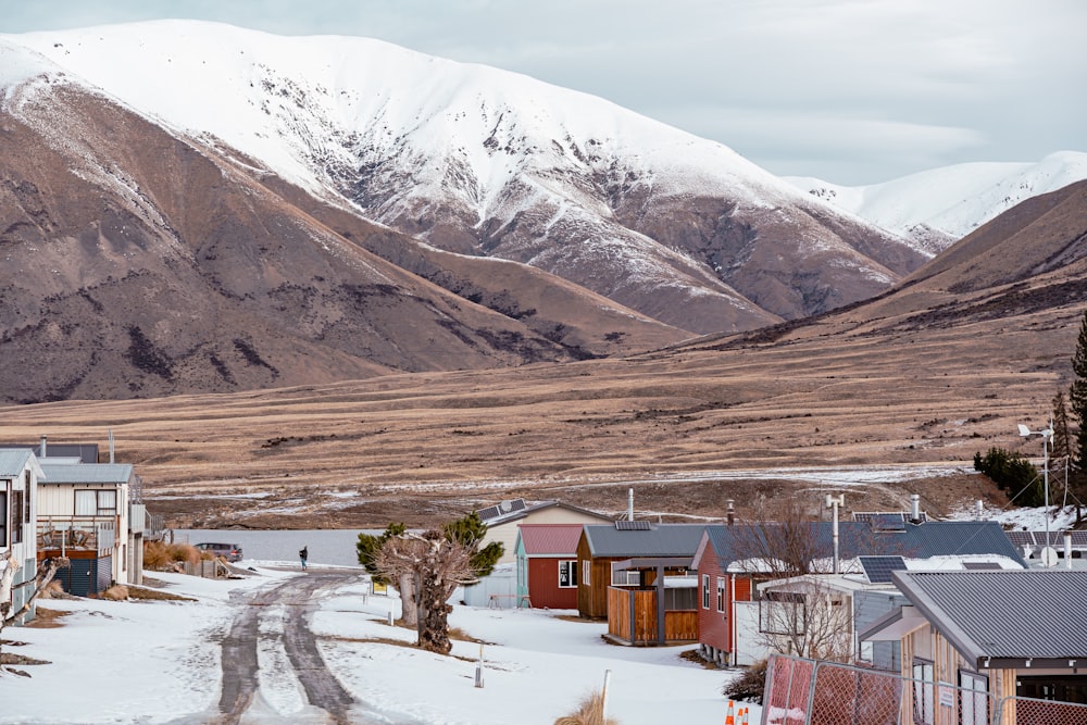 a group of buildings in a snowy area with mountains in the background