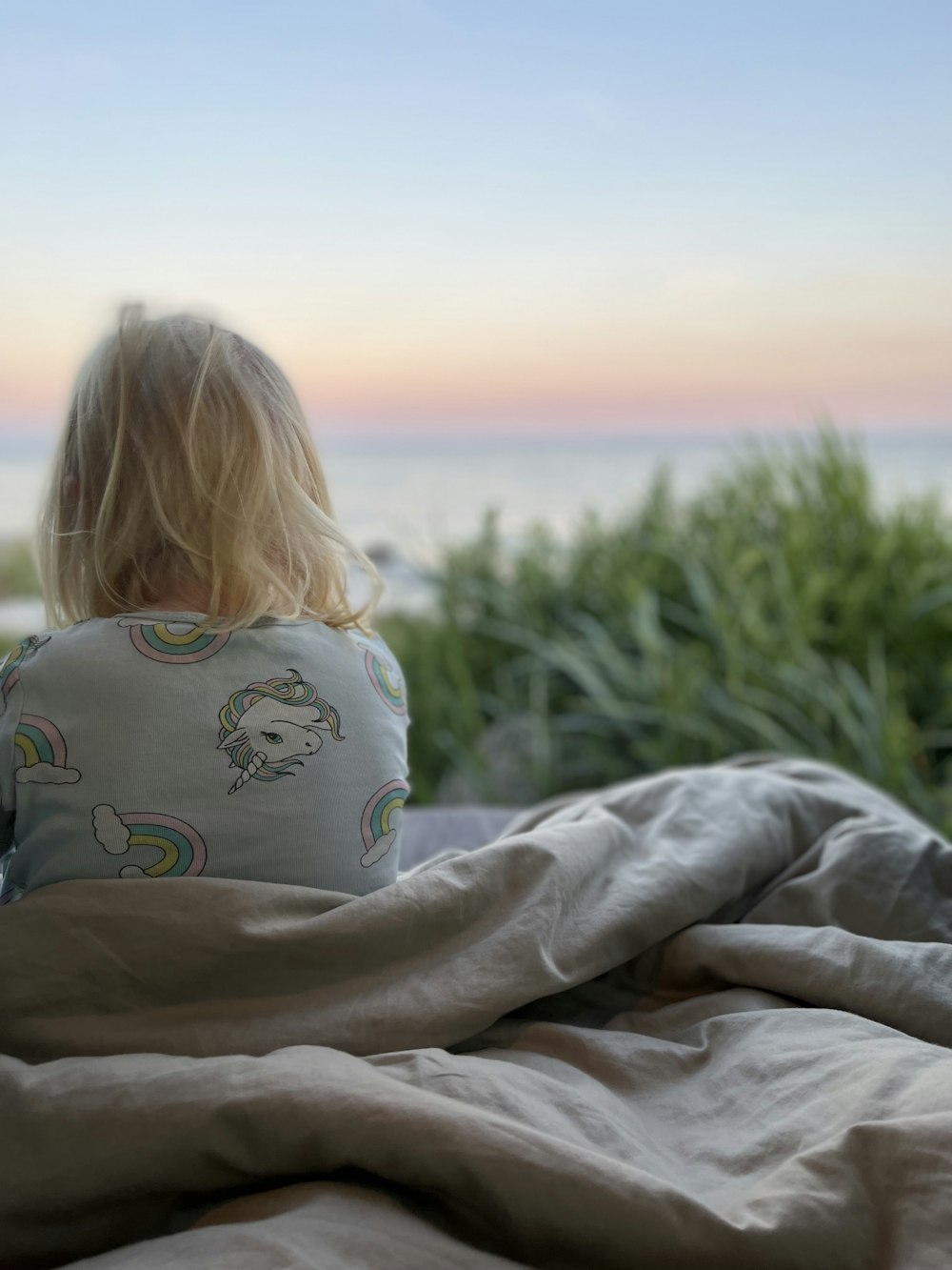 a person lying on a blanket looking at the water