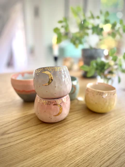 Brightly colored ceramic cups arranged artistically on a wooden table.