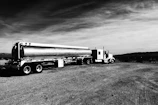 A black gold branded tanker truck parked at an industrial site during sunrise.