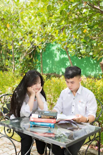a boy and girl sitting at a table with books and books