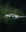 A white drone with four propellers is captured mid-flight against a blurred, dark green background. The drone is centrally composed, with its camera and sensors clearly visible, giving an impression of precision and advanced technology.
